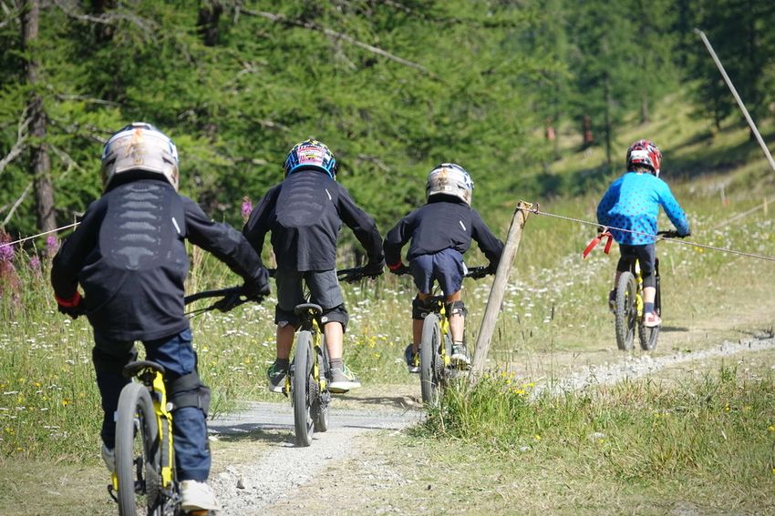 Quatre jeunes vététistes casqués sur un sentier du bike park de Montgenèvre, en été