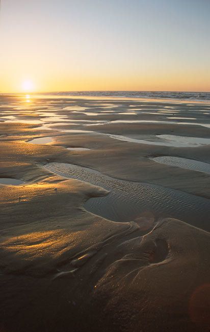 Le sable mouillé et les flaques laissées par la marée au coucher du soleil, sur la plage de Houlgate