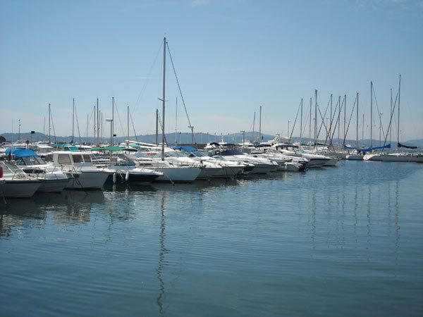 Voiliers et bateaux à moteur amarrés dans le port de plaisance de Cavalaire-sur-Mer, les collines au fond