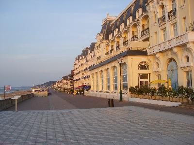 La façade du Grand Hôtel de Cabourg sur la promenade Marcel-Proust, en fin de journée, la plage à gauche