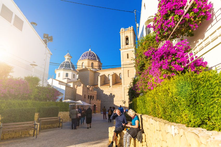 L'église d'Altea et ses coupoles de tuiles bleues, vues d'une ruelle fleurie de bougainvilliers