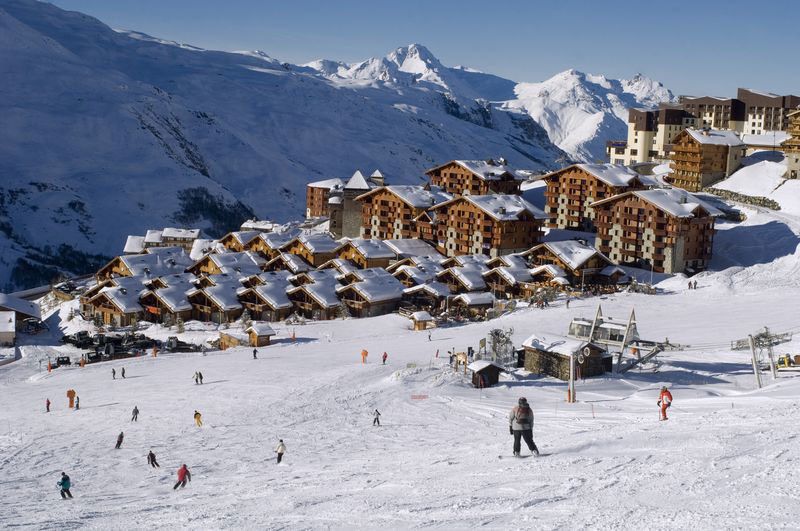 Chalets et résidences enneigés au pied des pistes dans la vallée des Belleville, skieurs sur le front de neige